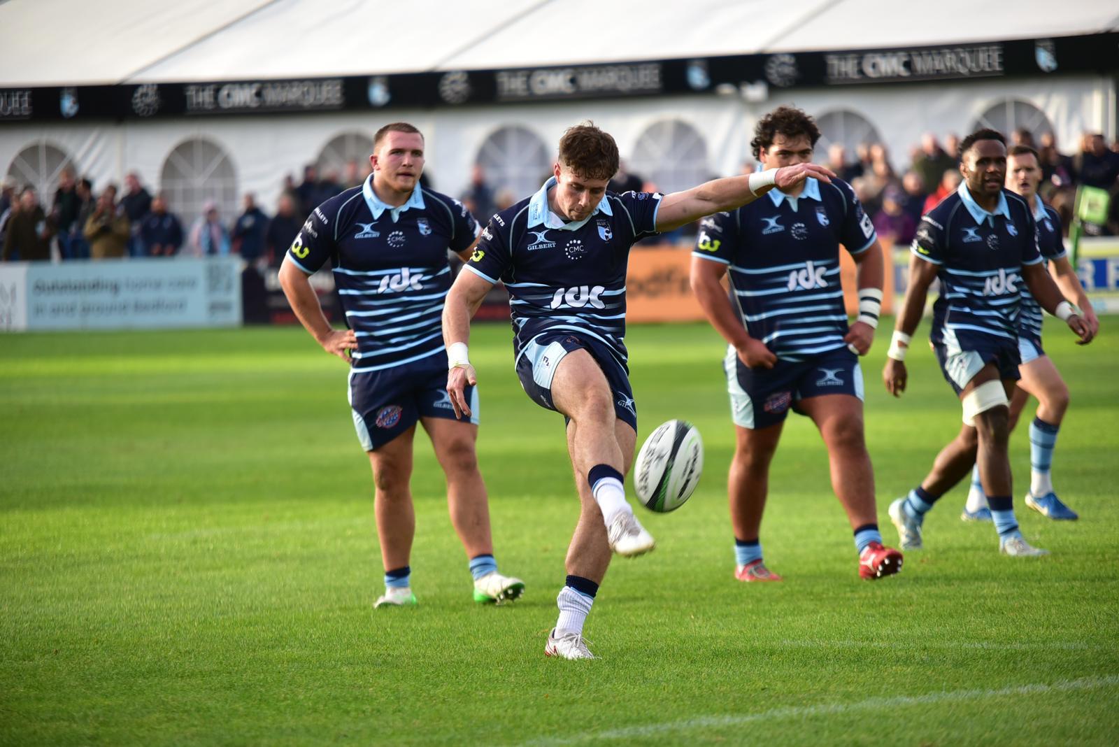 Tom Price taking a kick with teammates behind him